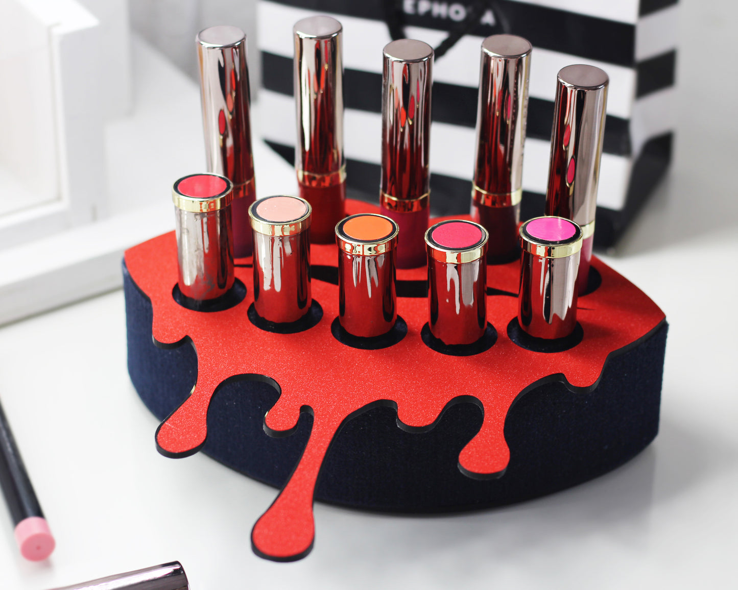 Small Lip Design Lipstick Organizer holding 10 lipsticks mounted on the wall with lipstick easily accessible and organized. Hanging Lipstick Holder that looks like wall art. Shown sitting on a makeup vanity.