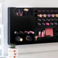 Black Ultra Complete Makeup Solution Organizer shown mounted on the wall holding lipsticks, lip glosses, nail polishes, brushes, sunglasses and more by keeping items accessible and off of the counter. Shown next to a makeup vanity with samples of suggested items the organizer can hold. Tilted to the right to show the wall mounted makeup organizer at a different angle while still on the wall.