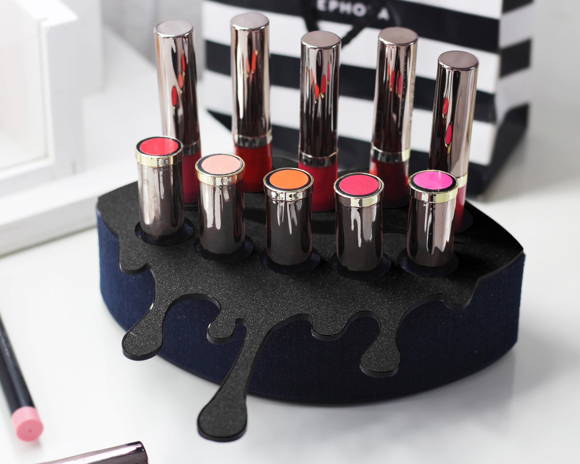 Small Lip Design Lipstick Organizer holding 10 lipsticks mounted on the wall with lipstick easily accessible and organized. Hanging Lipstick Holder that looks like wall art. Shown sitting on a makeup vanity.