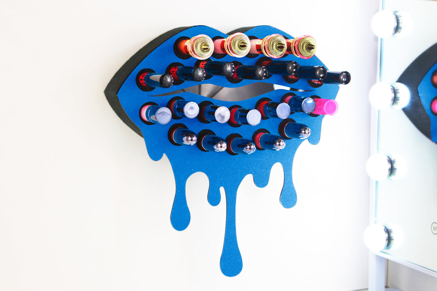 Blue Medium Lip Design Lipstick Organizer holding 23 lipsticks mounted on the wall, keeping lipstick organized and easy to reach. This wall mounted makeup organizer looks like art on the wall of your bathroom or makeup room.