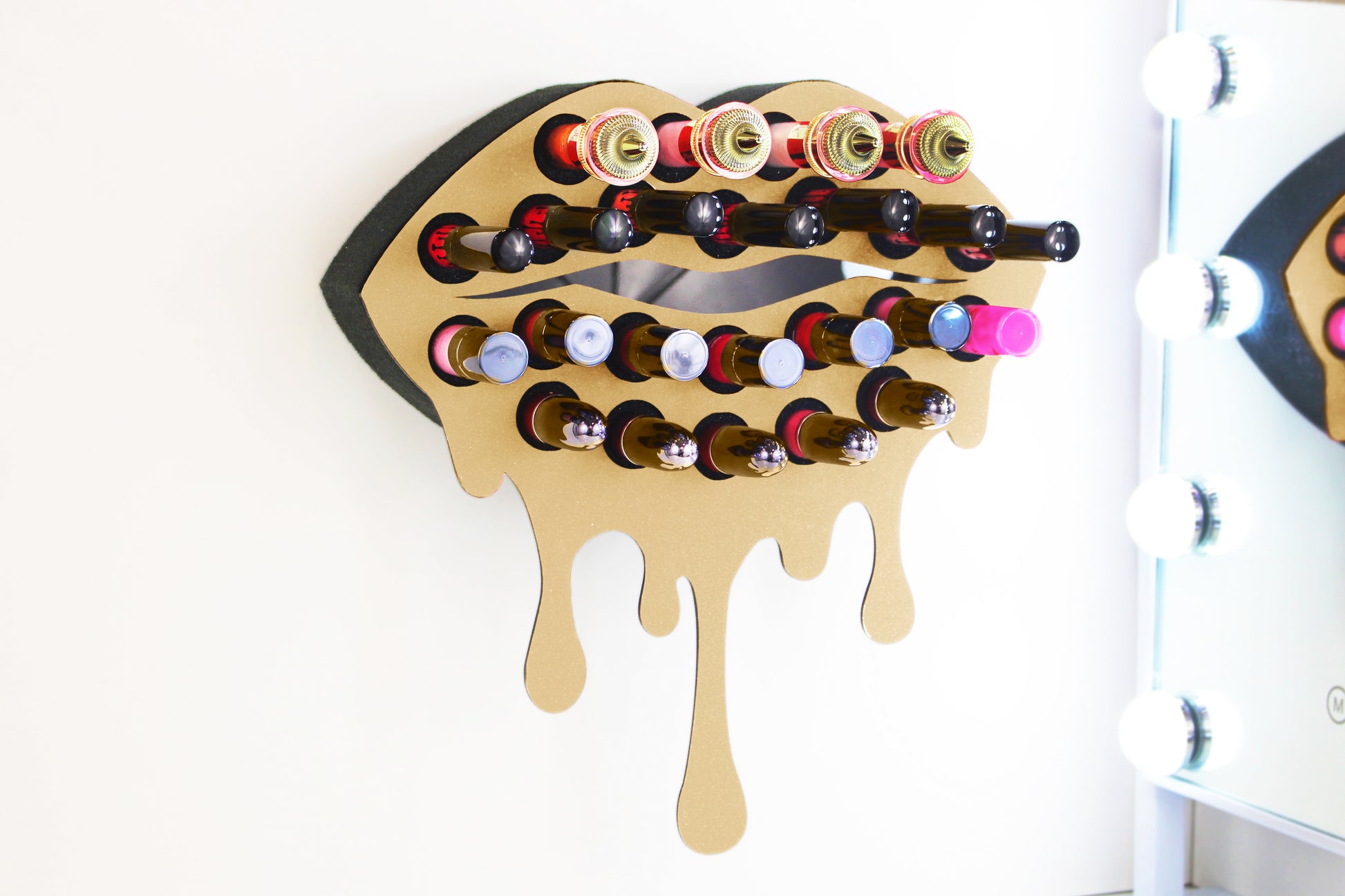 Gold Medium Lip Design Lipstick Organizer holding 23 lipsticks mounted on the wall, keeping lipstick organized and easy to reach. This wall mounted makeup organizer looks like art on the wall of your bathroom or makeup room.