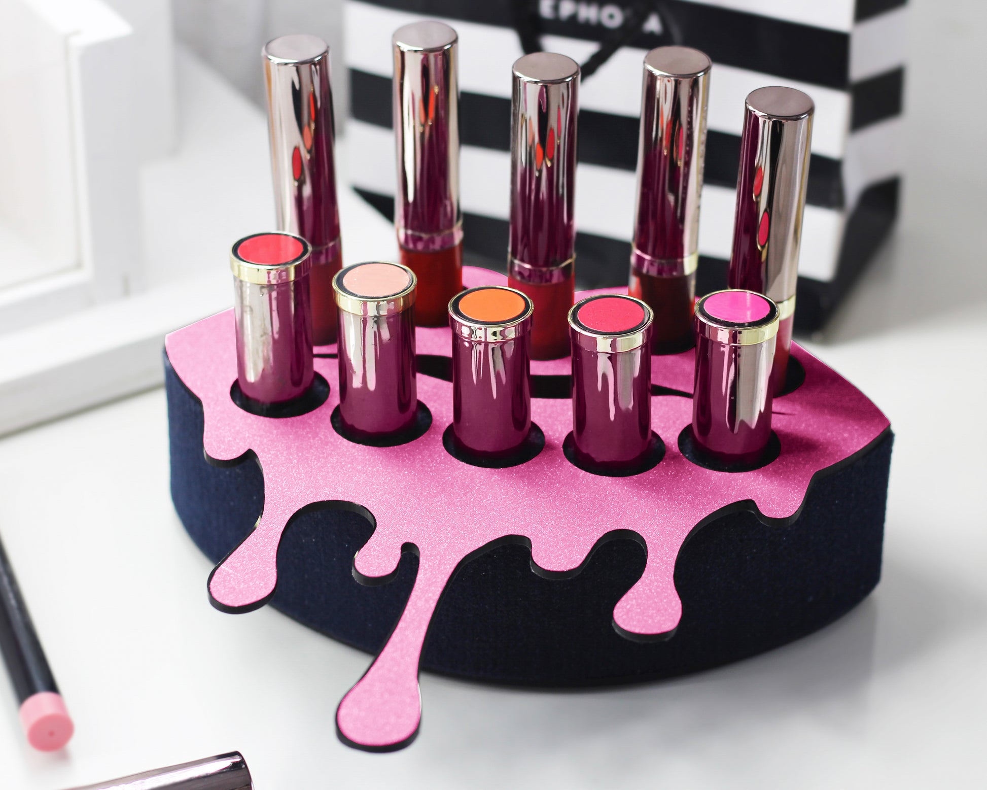 Small Lip Design Lipstick Organizer holding 10 lipsticks mounted on the wall with lipstick easily accessible and organized. Hanging Lipstick Holder that looks like wall art. Shown sitting on a makeup vanity.