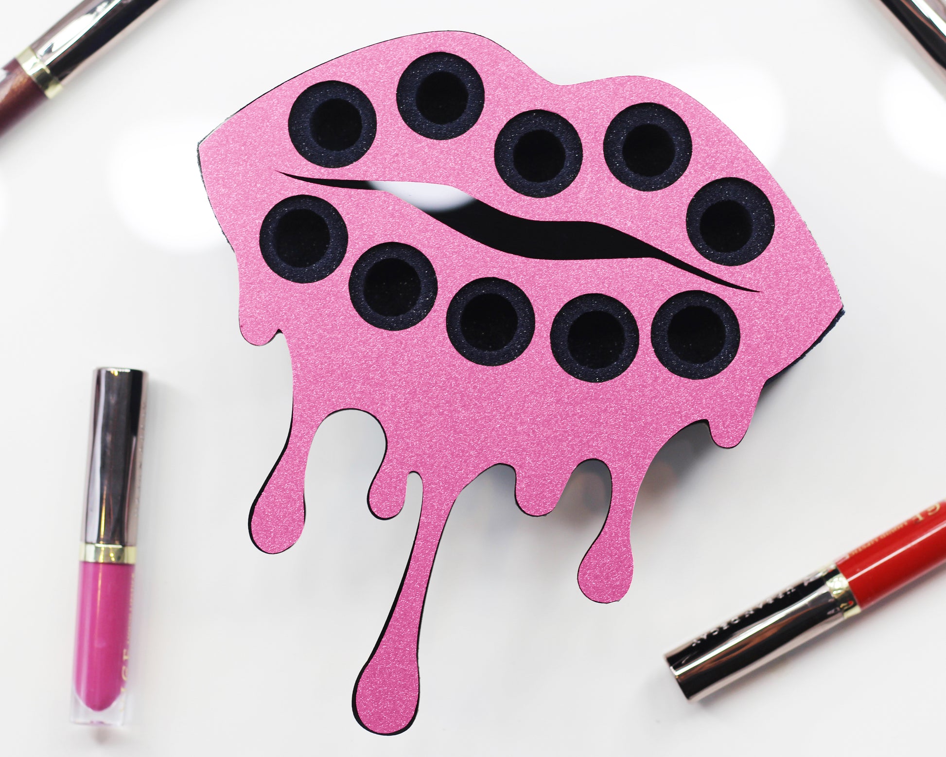 Empty Small Lip Design Lipstick Organizer holding 10 lipsticks mounted on the wall with lipstick easily accessible and organized. Hanging Lipstick Holder that looks like wall art. Shown with lipstick next to the organizer.