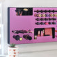 Mirror Pink Ultra Complete Makeup Solution Organizer shown mounted on the wall holding lipsticks, lip glosses, nail polishes, brushes, sunglasses and more by keeping items accessible and off of the counter. Shown next to a makeup vanity with samples of suggested items the organizer can hold. Tilted to the right to show the wall mounted makeup organizer at a different angle while still on the wall.