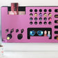 Mirror Pink Ultra Complete Makeup Solution Organizer shown mounted on the wall holding lipsticks, lip glosses, nail polishes, brushes, sunglasses and more by keeping items accessible and off of the counter. Shown next to a makeup vanity with samples of suggested items the organizer can hold.