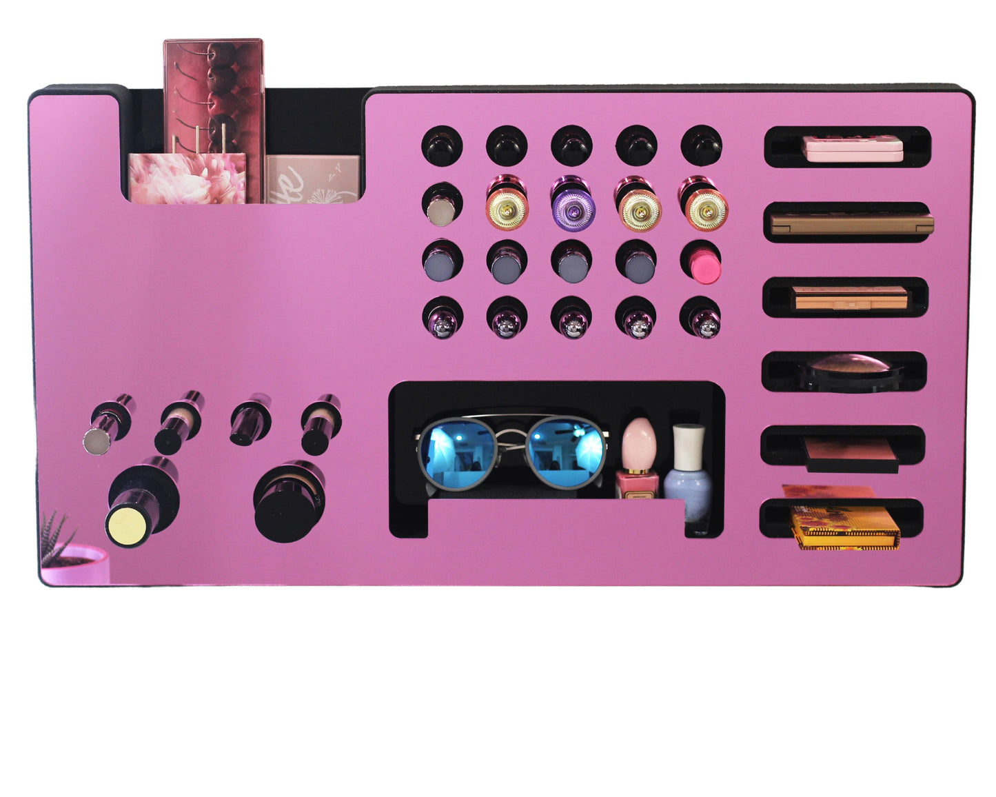 Mirror Pink Ultra Complete Makeup Solution Organizer shown mounted on the wall holding lipsticks, lip glosses, nail polishes, brushes, sunglasses and more by keeping items accessible and off of the counter. Shown next to a makeup vanity with samples of suggested items the organizer can hold. Shown with a white background.